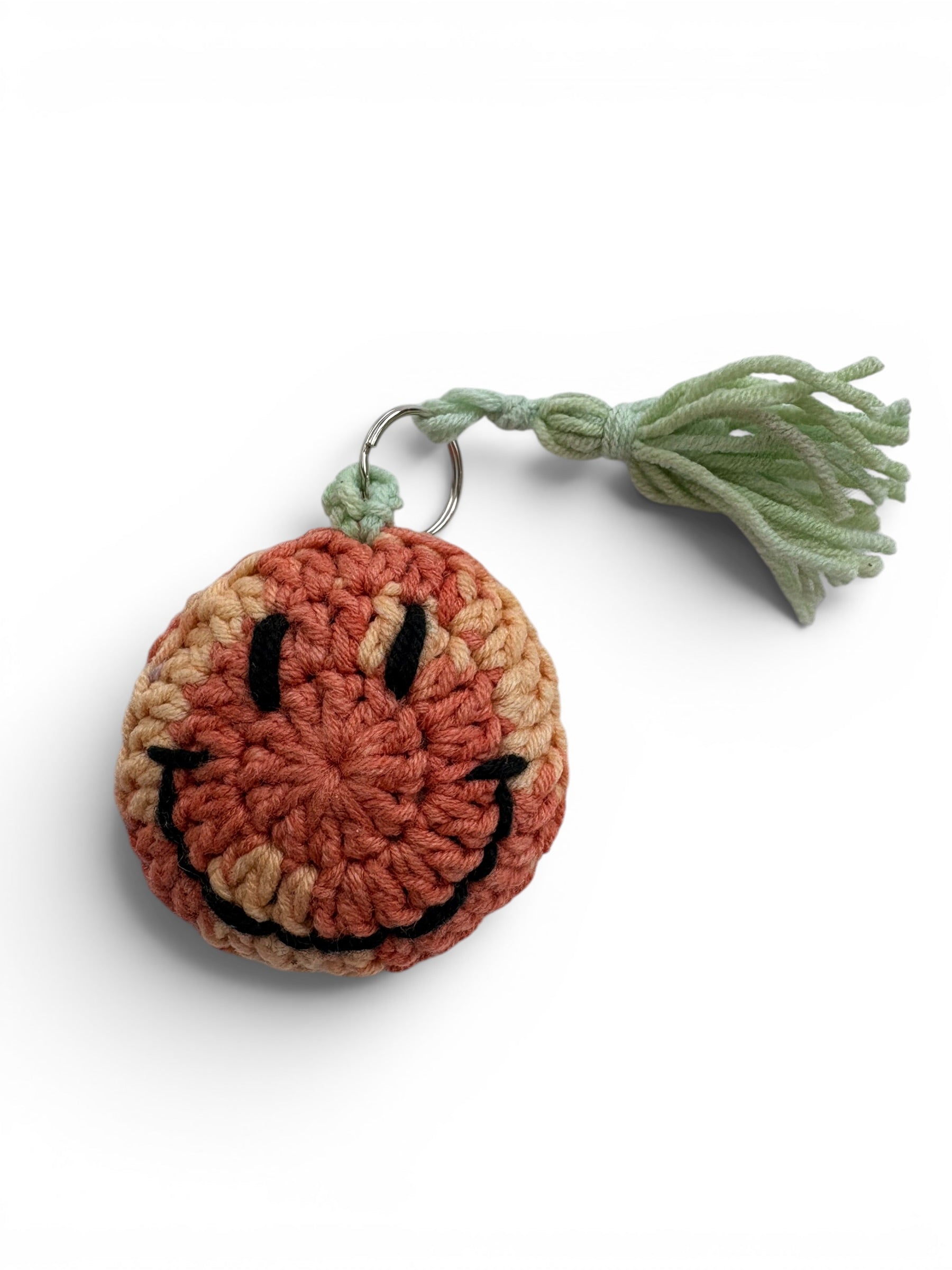Crocheted smiley face keychain with a green tassel 
