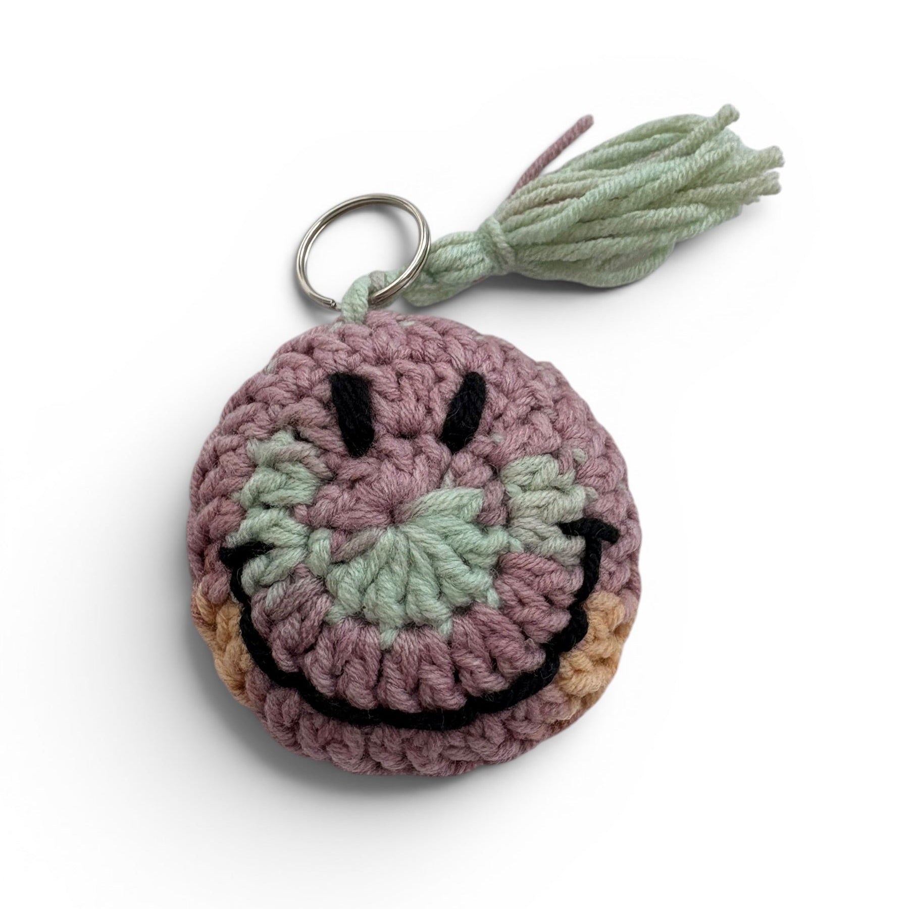 Crocheted keychain with a smiley face design and tassel