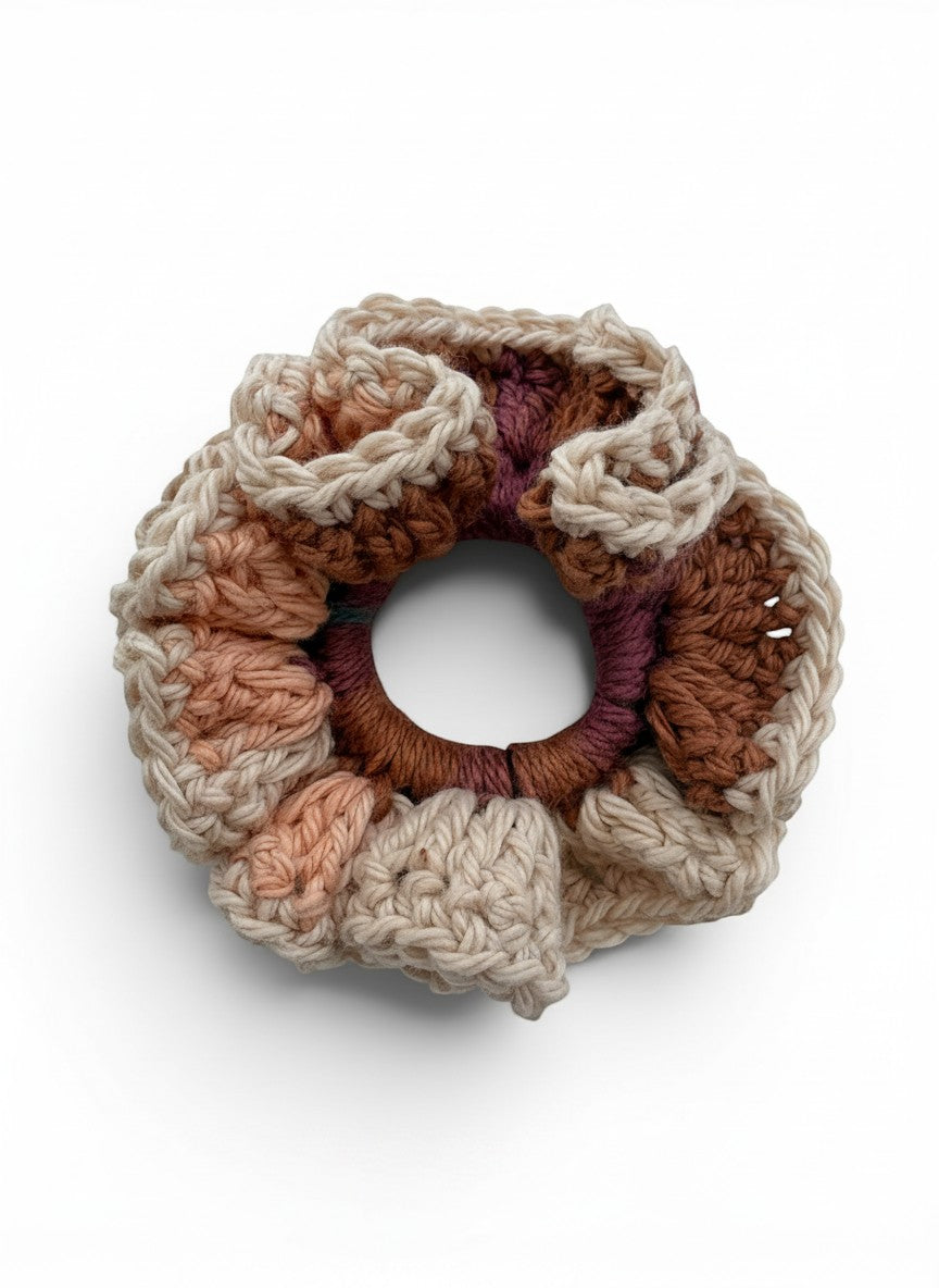Criminal Crochet handmade scrunchie in earthy tones of beige, brown, and plum with a textured crochet pattern.