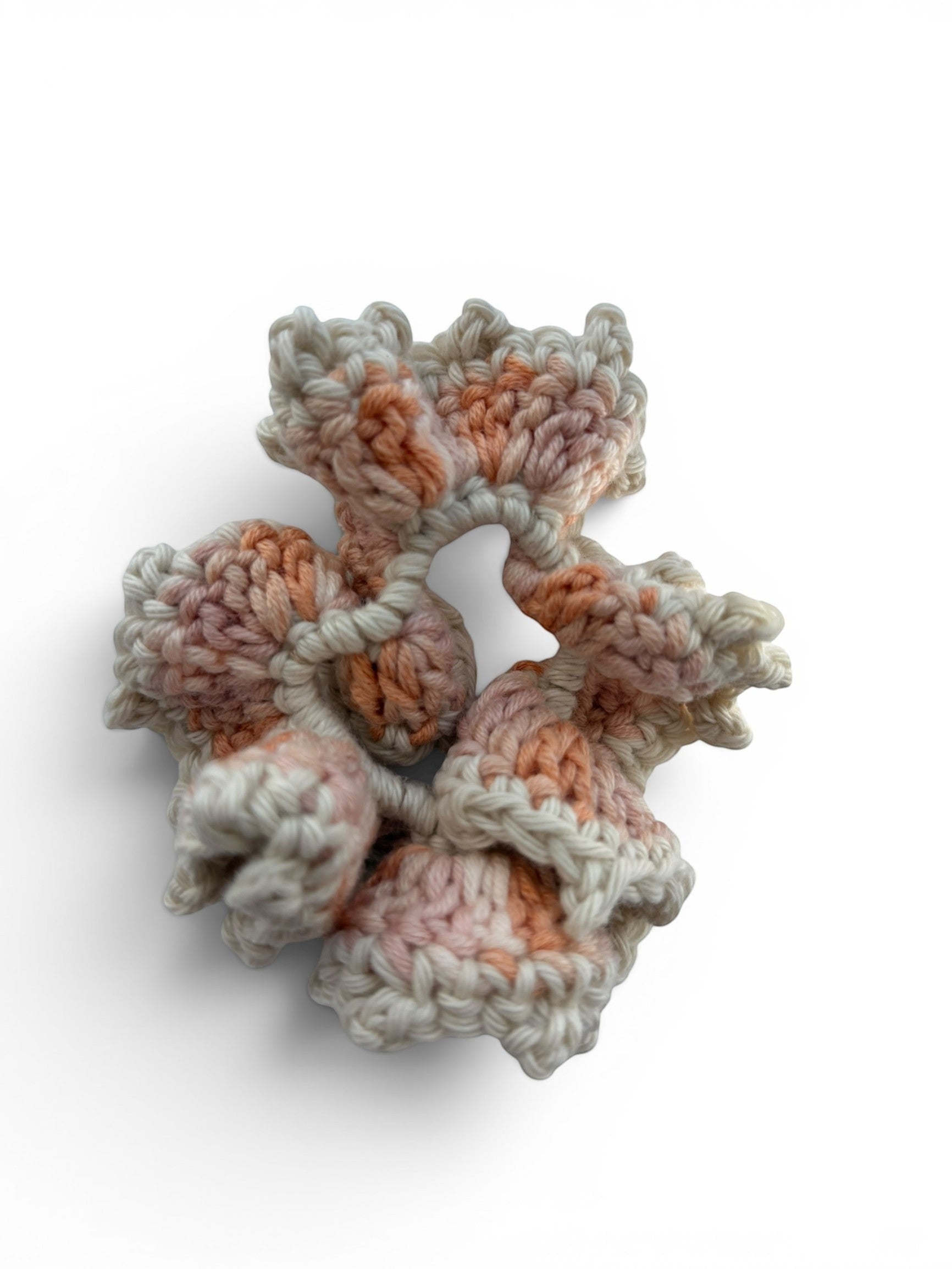 Criminal Crochet handmade scrunchie in cream with pink and orange marbled yarn, featuring intricate crochet texture.